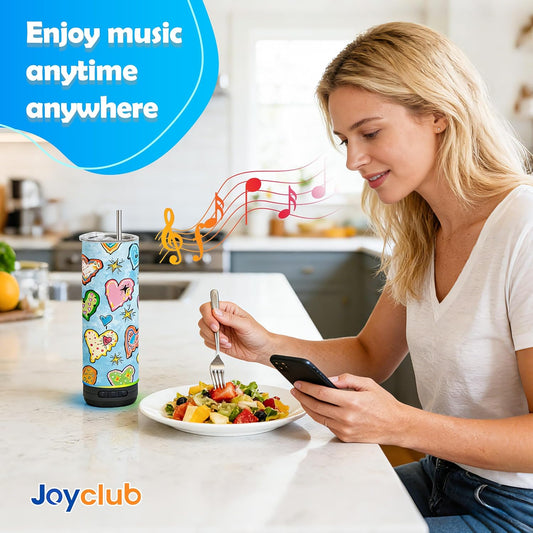 Woman using a decorated speaker tumbler beside a phone at a kitchen counter